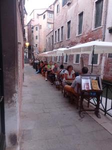 un grupo de personas sentadas en bancos en una calle en Ca’Barbarigo, en Venecia 6 fotos más