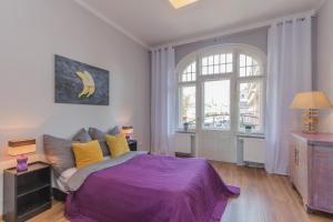 ein Schlafzimmer mit einem lila Bett und einem Fenster in der Unterkunft visit baltic - Centrum in Świnoujście