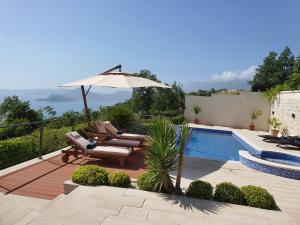 un patio con sombrilla, sillas y piscina en Luxury Villa Crystal Blue, en Sveti Stefan