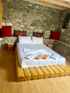 a bed in a room with a stone wall at Kubeja Guest House in Gjirokastër