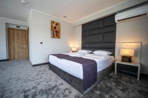 - une chambre avec un grand lit et une tête de lit noire dans l'établissement Hotel Caesar 2, à Kardjali
