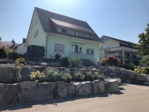 a house with a stone retaining wall in front of a yard at Ferienwohnung Emily in Friesenheim