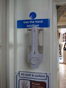 a sign that says use the hand sanitizer on a machine at The Londesborough Arms bar with en-suite rooms in Market Weighton