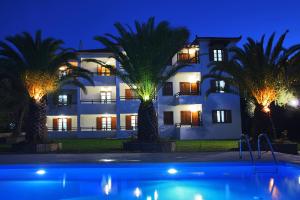 a building with palm trees in front of a swimming pool at Villa Maro in Skopelos Town