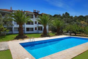 a swimming pool in front of a house with palm trees at Villa Maro in Skopelos Town