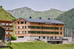 a large building with mountains in the background at Rössle Appartements in Faschina