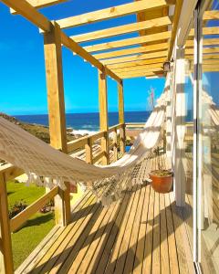 a hammock on a deck with a view of the ocean at Casa no Farol in Camacho
