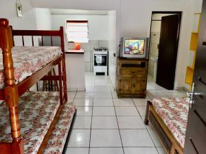 a room with bunk beds and a kitchen with a television at Chalés Damata in Ubatuba