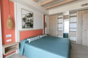 1 dormitorio con cama azul y pared de color naranja en The White Apartments, en San Antonio