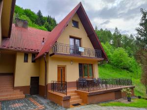 uma casa com um telhado vermelho e uma varanda em Agroturystyka u Zbyszka em Tylmanowa