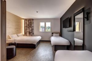 a hotel room with two beds and a tv at B&B HOTEL Evian Publier in Publier