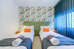 sypialnia z 2 łóżkami i pomarańczowymi poduszkami w obiekcie Colorful & Spacious Home with Yard - Close to Xemxija Bay w mieście St Paul's Bay