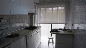 eine Küche mit einem Waschbecken, einem Fenster und einem Stuhl in der Unterkunft My Sunny Apartment Barra in Praia da Barra