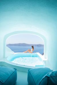 a woman sitting in a swimming pool in a house at Sun Rocks Boutique Hotel in Firostefani
