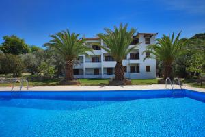 a swimming pool in front of a house with palm trees at Villa Maro in Skopelos Town