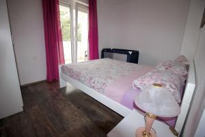 a bedroom with a bed and a table with a lamp at Apartman Mirno More in Selce