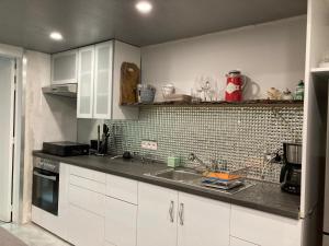 een keuken met witte kasten en een wastafel bij Vakantie Villa Hengelhoef in Zonhovenheide