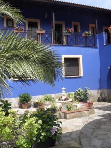 um edifício azul com plantas em frente em Apartamentos y Habitaciones Casa Bego em Valdredo