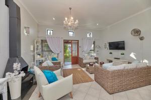 Una sala de estar con muebles blancos y una lámpara de araña. en Fraai Uitzicht Struisbaai, en Struisbaai