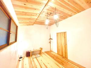 an empty room with a wooden ceiling and a door at 古民家ステイMatoba in Miyoshi
