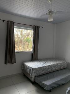 a bedroom with a bed and a window at Casa temporada in Florianópolis