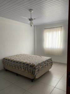 Cama en habitación con ventilador de techo en Casa temporada en Florianópolis