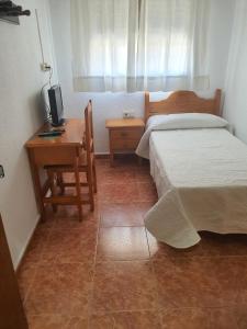 - une chambre avec un lit et un bureau avec un ordinateur dans l'établissement Los Príncipes, à Palos de la Frontera