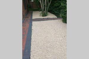 a garden with white gravel and a brick walkway at The Bungalow in Chesterton