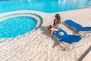 a woman sitting on a beach chair next to a pool at Pickalbatros Aqua Blu Resort - Hurghada in Hurghada