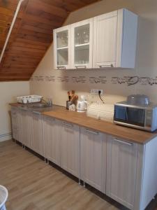a kitchen with white cabinets and a wooden counter top at Toldi Apartman in Keszthely