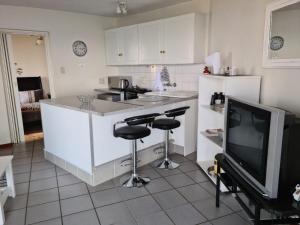 a kitchen with two bar stools and a tv at Kosmos View Luxury Apartments in Hartbeespoort