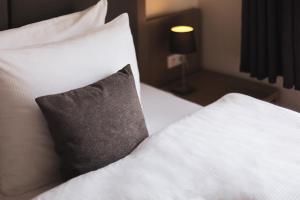 a bed with white sheets and a gray pillow at Novum Hotel Holstenwall Hamburg Neustadt in Hamburg