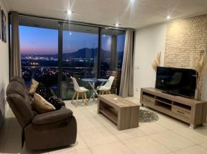 a living room with a television and a couch and a table at On the GBay Villa in Gordonʼs Bay