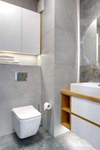 La salle de bains est pourvue de toilettes blanches et d'un lavabo. dans l'établissement Essence Apartments Amber, à Poznań