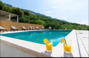 twee glazen sinaasappelsap naast een zwembad bij Kuca za odmor Veronika in Jesenice