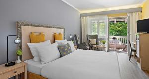 a bedroom with a large white bed and a balcony at Hotel St Leonhard in Bad Griesbach