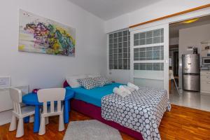 een slaapkamer met een blauw bed en een tafel en stoelen bij Crikvenica Right On The Beach in Crikvenica