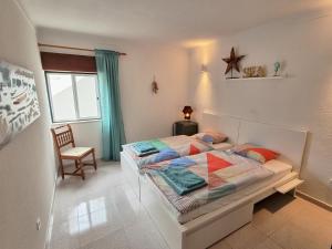 1 dormitorio con 1 cama, 1 silla y 1 ventana en Casa Mar e Sol, NEW apartment near the beach with balcony, en Sesimbra