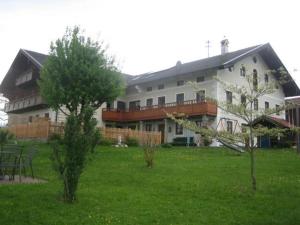 - un grand bâtiment blanc avec une cour arborée dans l'établissement Schellenberger Hof, à Soyen