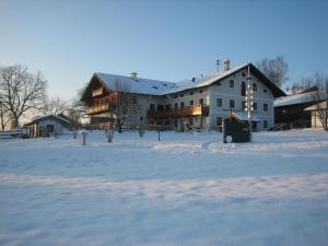 a large house in a snowy field with a building at Schellenberger Hof in Soyen