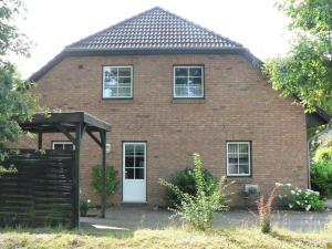 una casa de ladrillo rojo con puerta blanca en Ferienwohnungen Torfweg, en Weddingstedt