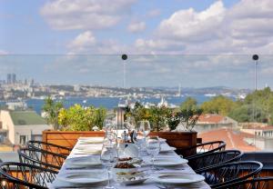 a long table with plates and wine glasses on a balcony at Orient Express & Spa by Orka Hotels in Istanbul