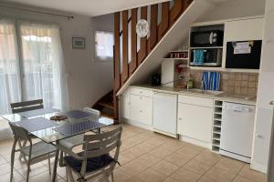 a kitchen with a dining table and a kitchen with a staircase at Super duplex bord de mer, histoire nature sport. in Merville-Franceville-Plage