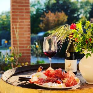 a plate of food and a glass of wine on a table at Casale Terre Rosse Garden in Saturnia +47 photos