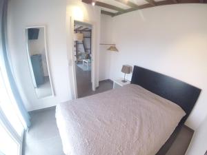 a white bedroom with a bed and a mirror at Casa Azul in Lourinhã