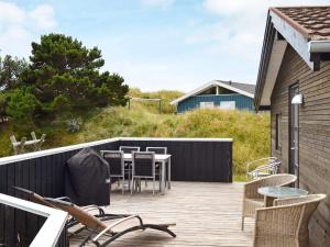 una terraza de madera con sillas y mesas en una casa en 6 person holiday home in Fanø, en Fanø