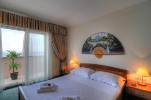 a bedroom with a large bed and a large window at Hotel Rosina in Makarska