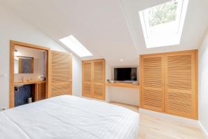 Résidence Les Suites du Port في أركاشون: غرفة نوم مع دواليب خشبية وسرير مع تلفزيون
