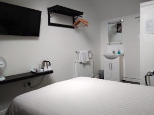 um quarto branco com uma cama e um lavatório em Comfort Guest House em Leicester