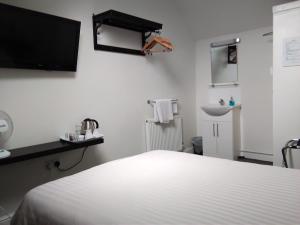 a white bedroom with a bed and a sink at Comfort Guest House in Leicester